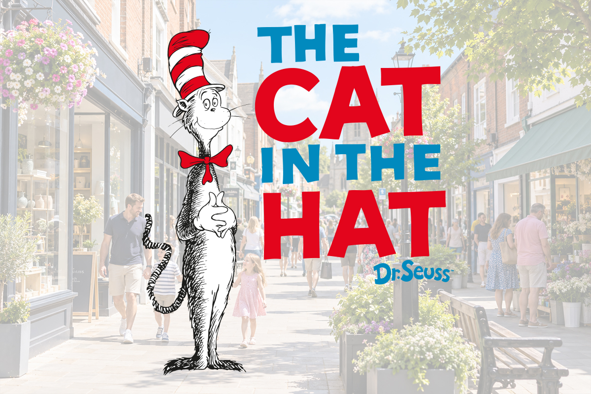 A hand holds a phone scanning a trail marker on a cobbled town street, with the Cat in the Hat's hat appearing in AR